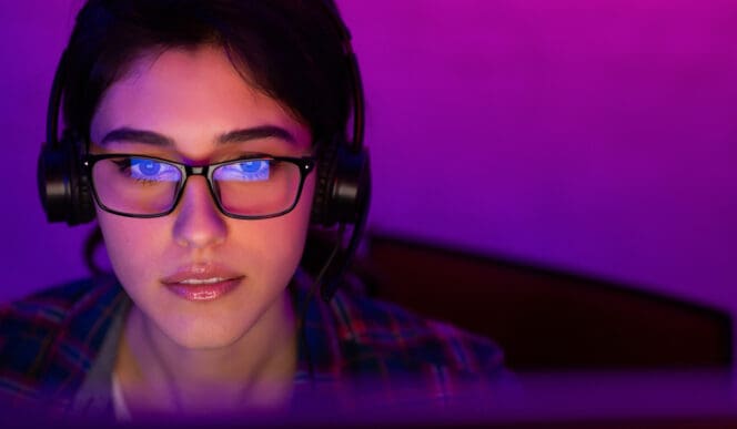 Woman wearing gaming glasses in front of her computer