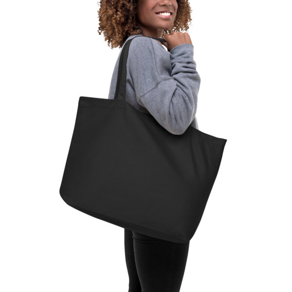 A woman holding a black tote bag