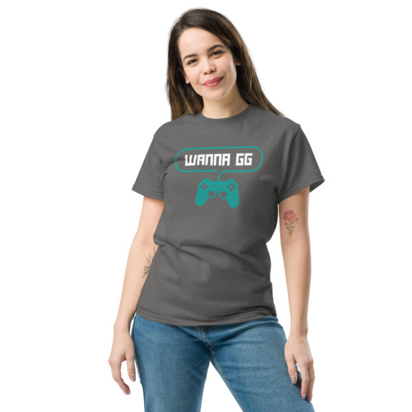 A woman posing head-on wearing a grey tshirt on which is written "wanna gg" in white with a green PlayStation controller underneath