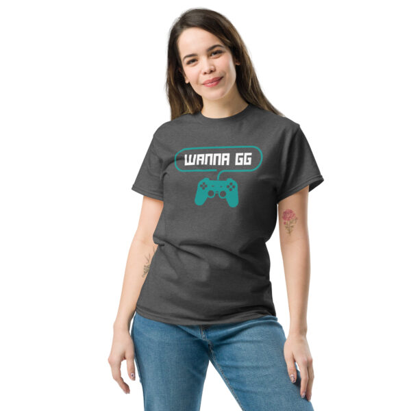 A woman posing head-on wearing a grey tshirt on which is written "wanna gg" in white with a green PlayStation controller underneath