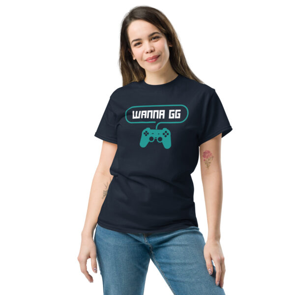 A woman posing head-on wearing a dark blue tshirt on which is written "wanna gg" in white with a green PlayStation controller underneath