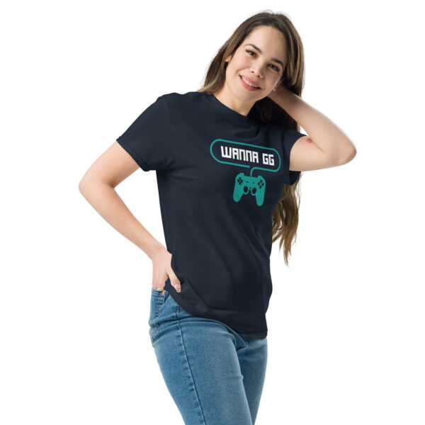 A woman posing head-on wearing a dark blue tshirt on which is written "wanna gg" in white with a green PlayStation controller underneath