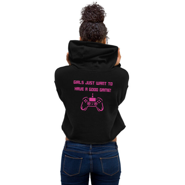 A woman posing from behind wearing a black sweatshirt on which is written "girls just want to have a good game!" in pink with a pink PlayStation controller underneath