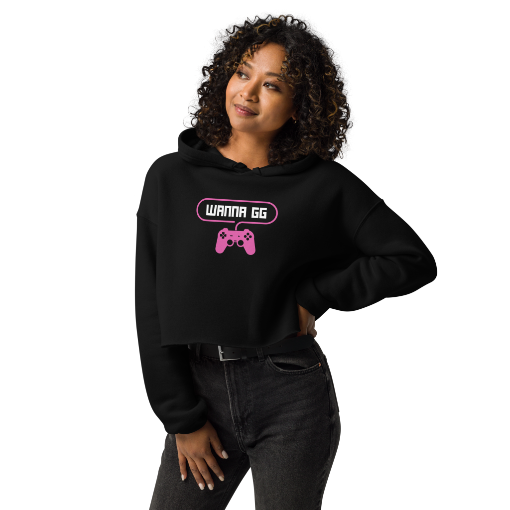 A woman posing head-on wearing a sweatshirt on which is written "wanna gg" in white with a pink PlayStation controller