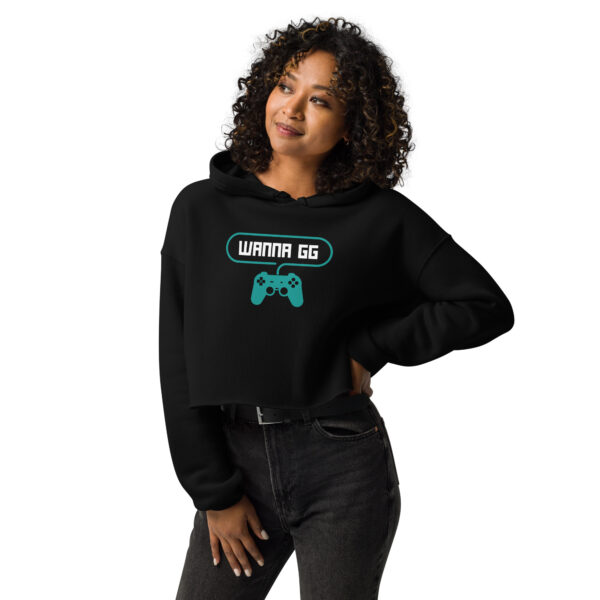 A woman posing head-on wearing black sweatshirt on which is writting "wanna gg" in white with a green PlayStation controller