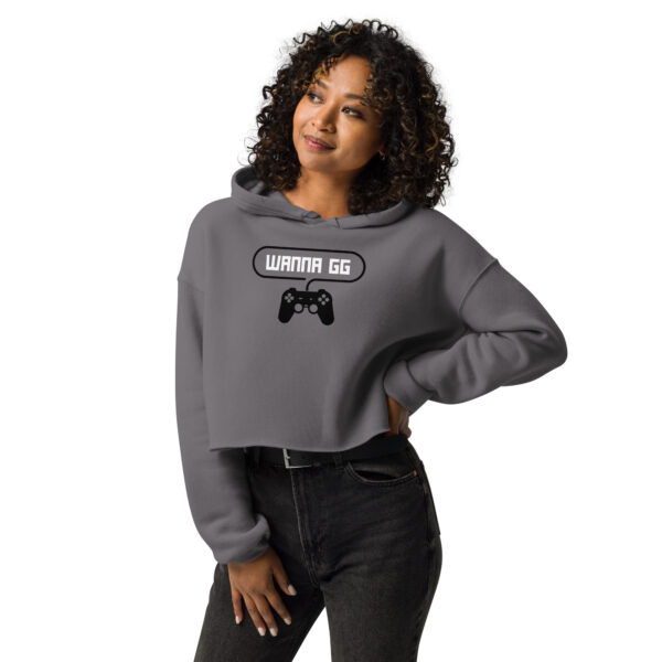 A woman posing head-on wearing a grey sweatshirt on which is writting "wanna gg" in white with a black PlayStation controller underneath