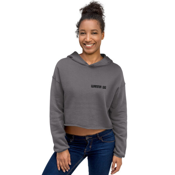 A woman poses head-on wearing a grey sweatshirt and it says "wanna gg" in black on the side