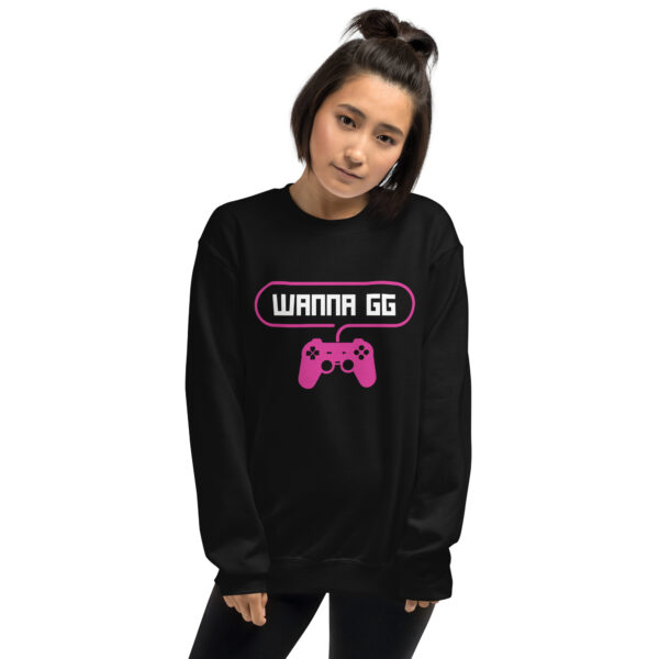 A woman poses head-on wearing a black sweater and it says "wanna gg" in white with a pink PlayStation controller