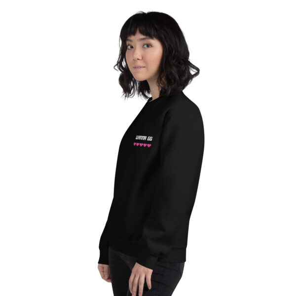 A woman poses sideways wearing a black sweater and it says "wanna gg" in white with 5 pink hearts underneath