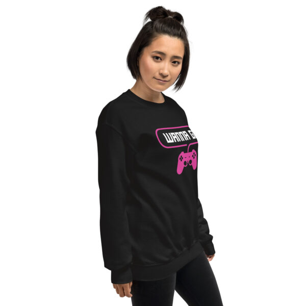 A woman poses sideway wearing a black sweater and it says "wanna gg" in white with a pink PlayStation controller